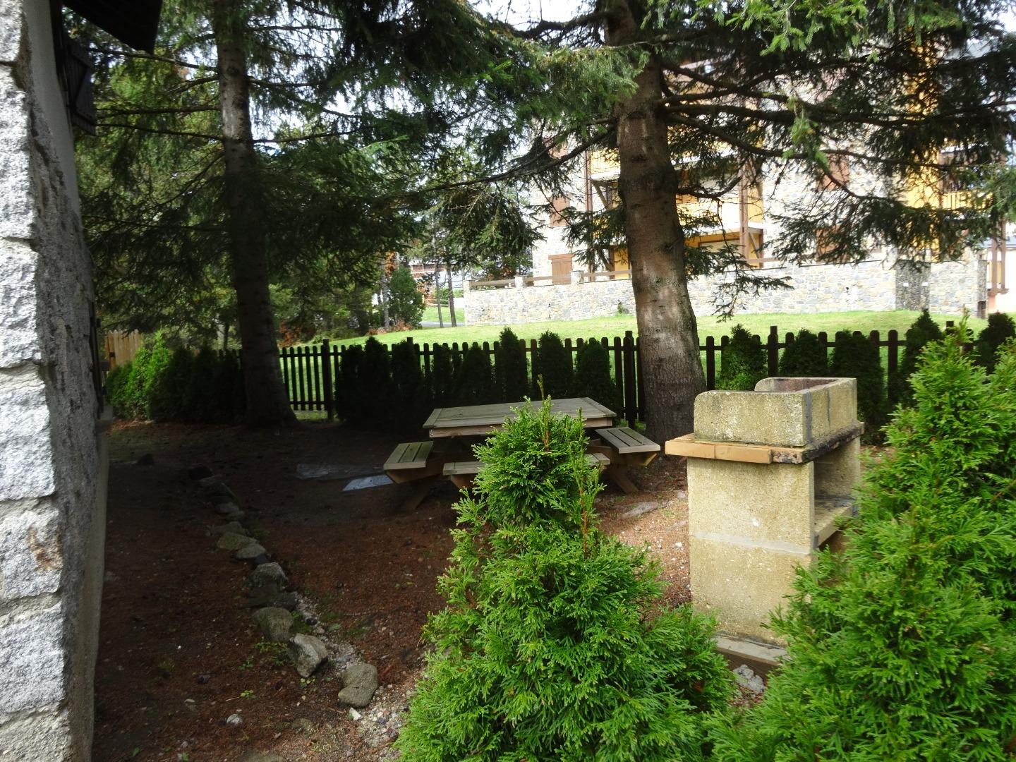 Jardin privatif entouré de petits arbres : table octogonale et barbecue